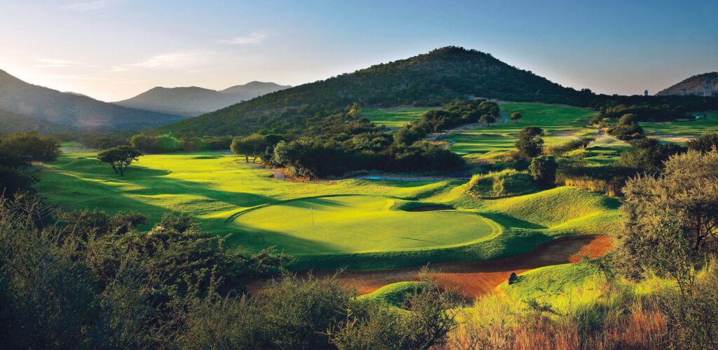 Rolling hills and pristine greens of the Lost City Golf Course at Sun City Resort, framed by the dramatic South African landscape.